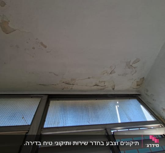 תקרה עם צבע מתקלף וסדקים מעל חלון לפני צביעה ותיקון